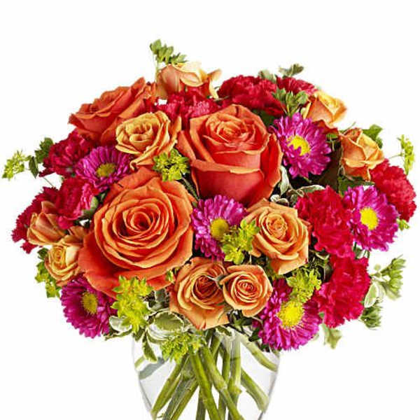 Orange roses and pink daisies in a clear glass vase