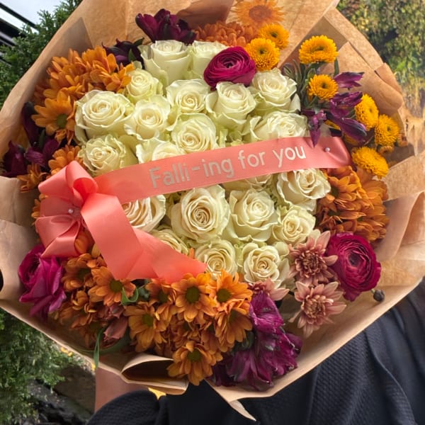 Bouquet of cream roses with orange and purple flowers, wrapped with a pink ribbon