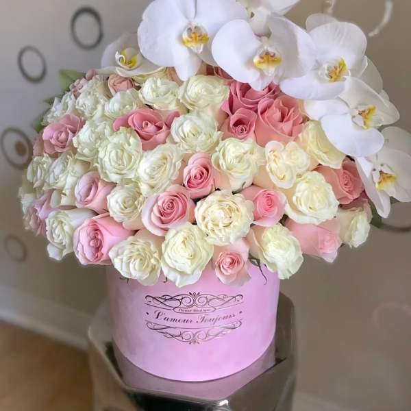 Pink and white roses with white orchids in a pink hat box