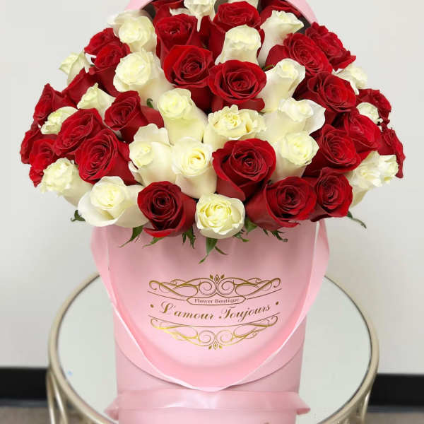 Bouquet of red and white roses in a pink hat box