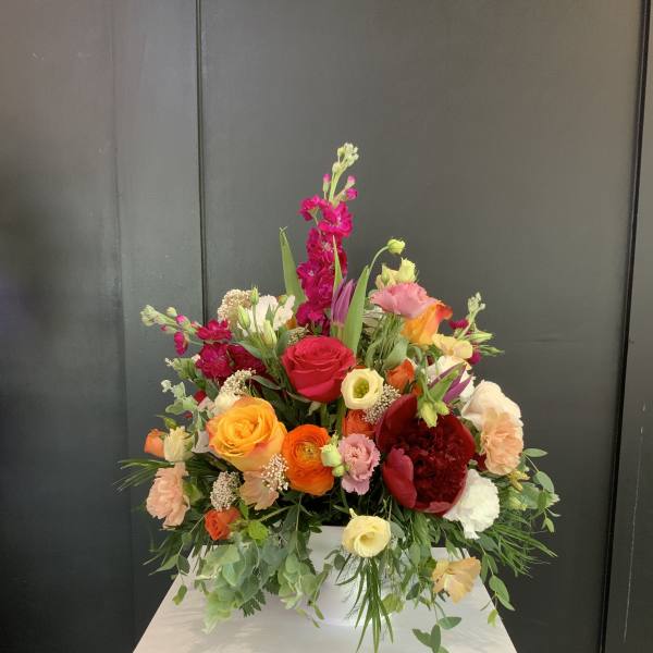 Colorful mixed flower arrangement in a white container