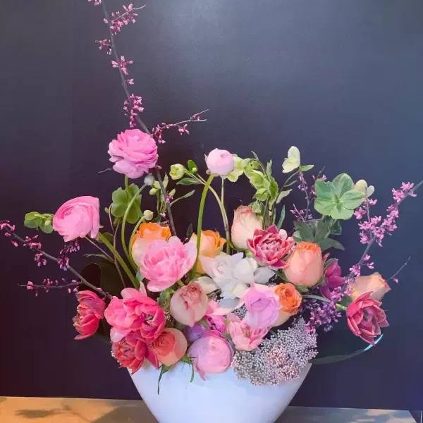 Pink and peach floral arrangement in a white vase