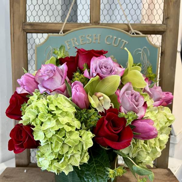 Bouquet of red and pink roses with green hydrangeas in a glass vase