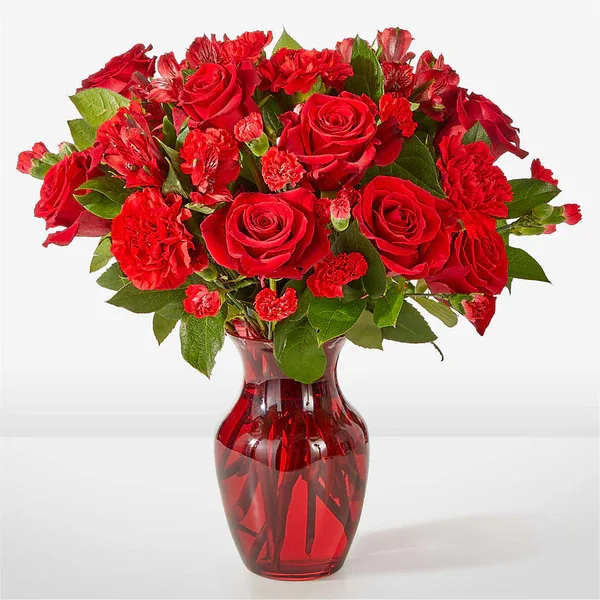 Red roses and carnations in a red glass vase