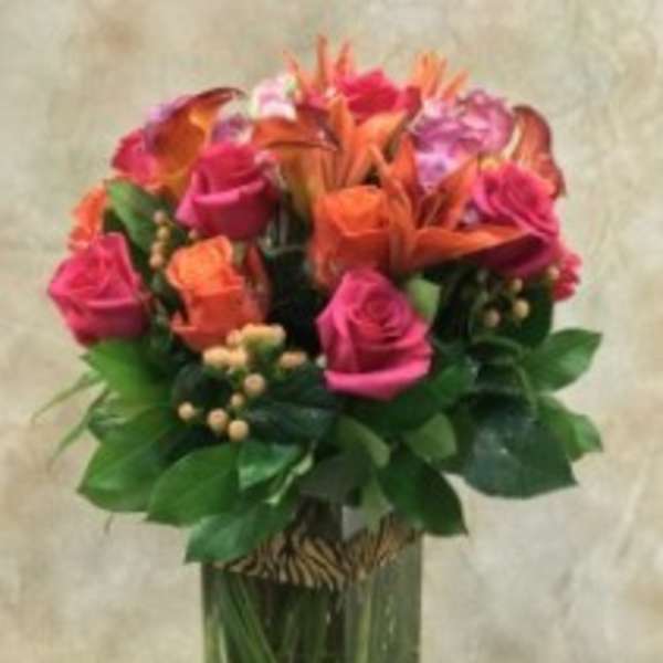 Bouquet of pink and orange flowers in a tall glass vase