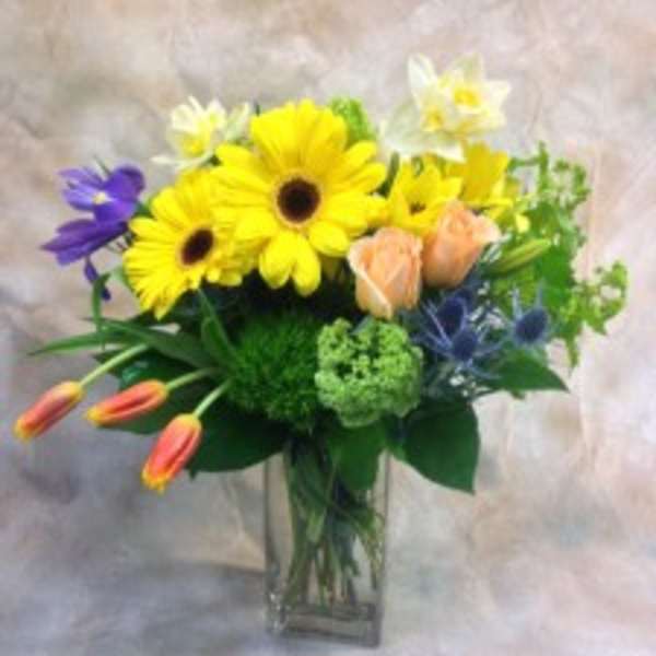 Mixed bouquet of yellow daisies and lilies in a clear glass vase