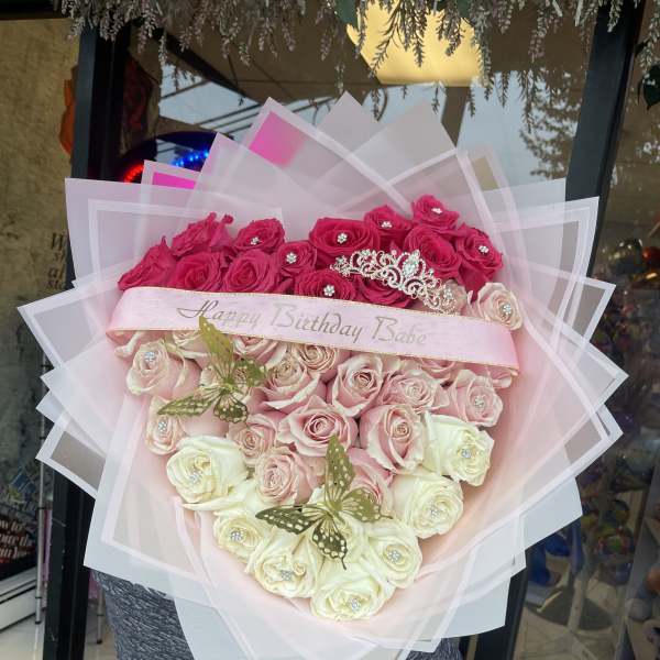 Heart-shaped bouquet of pink and white roses with a birthday ribbon