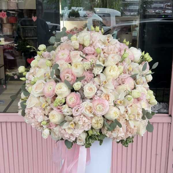 Large pastel bouquet of pink and white flowers in a tall white pedestal vase