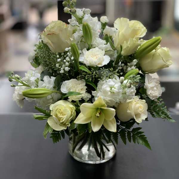 White and pale yellow floral arrangement in a clear glass vase