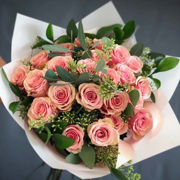 Bouquet of pink roses with white wrapping and greenery
