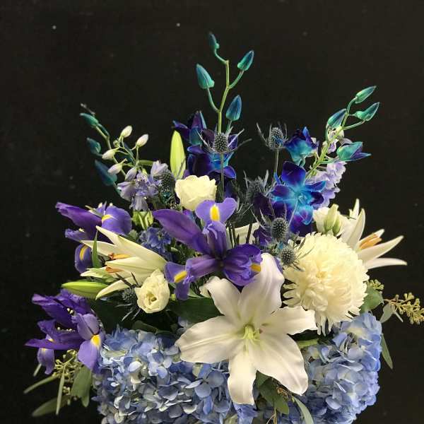 Blue and purple floral arrangement in a glass vase