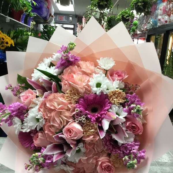Large bouquet of pink and white flowers wrapped in pale pink paper
