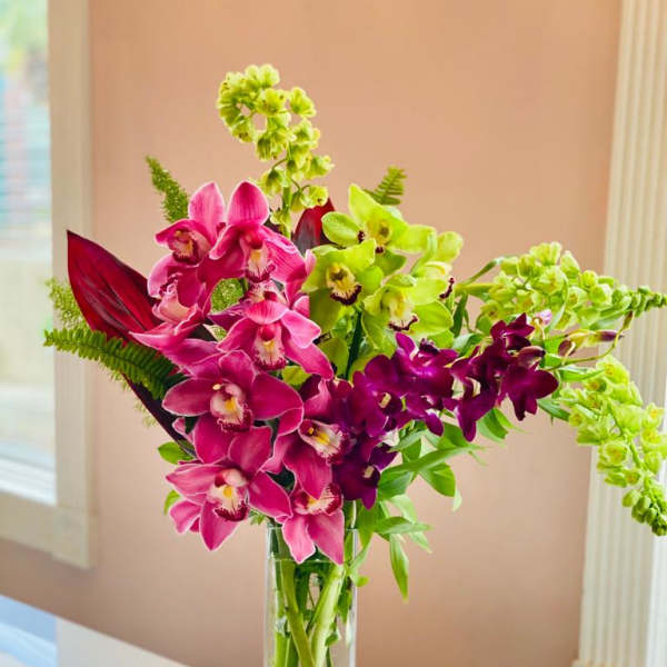 Pink and green orchids arranged in a tall clear vase