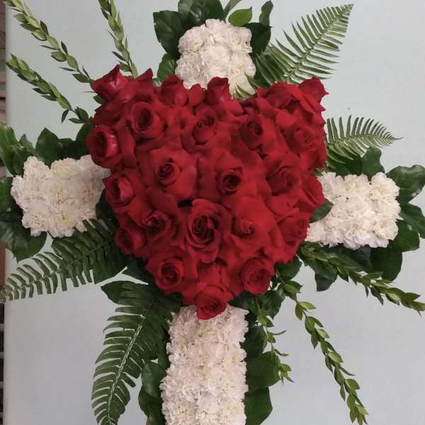 Red rose and white carnation cross-shaped floral tribute on an easel