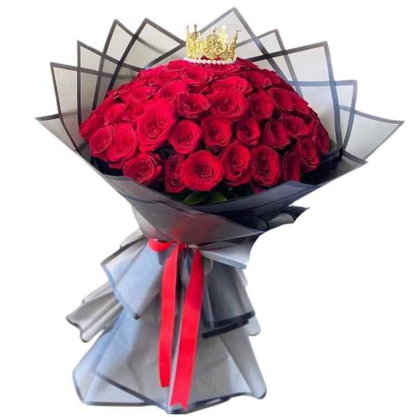 Large bouquet of red roses wrapped in black paper with a crown topper