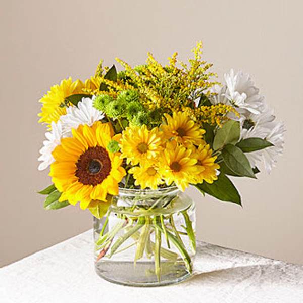 Bouquet of yellow and white flowers in a clear glass vase