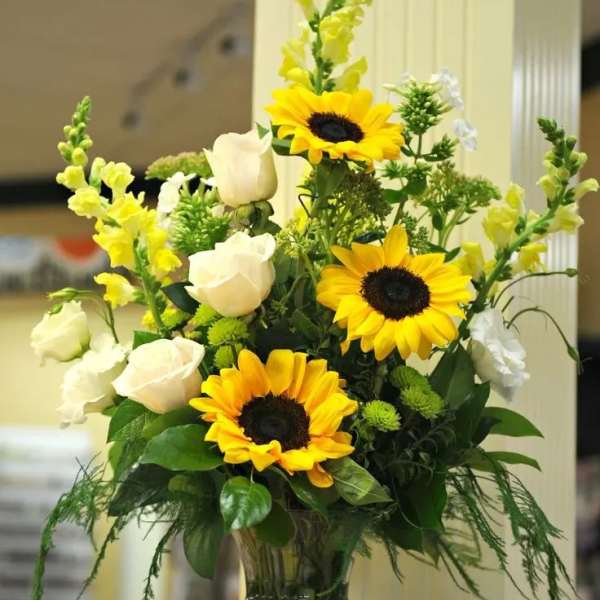 Sunflowers and white roses arranged in a clear glass vase