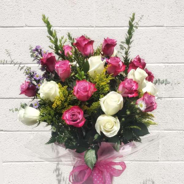 Bouquet of pink and white roses with small purple flowers in a wrapped vase