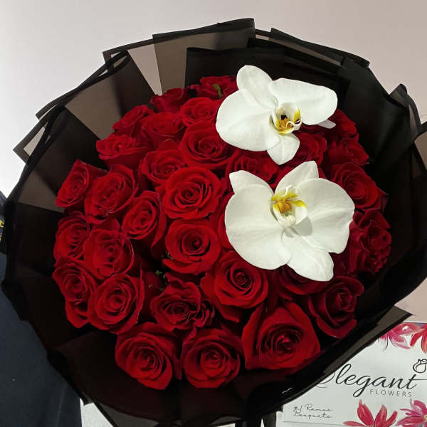 Bouquet of red roses with two white orchids wrapped in black paper