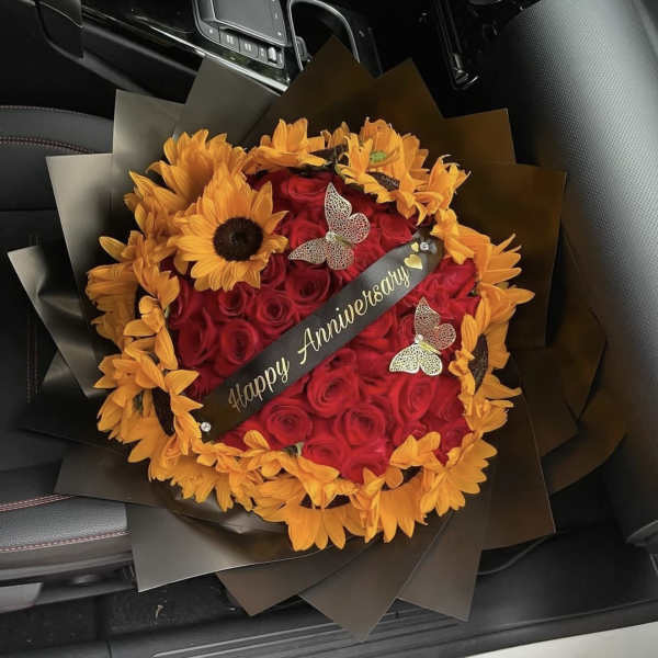 Red rose bouquet with orange sunflowers and a Happy Anniversary ribbon