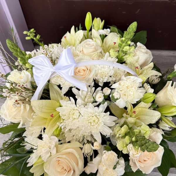 Cream bouquet with roses, lilies, and white blooms tied with a white ribbon