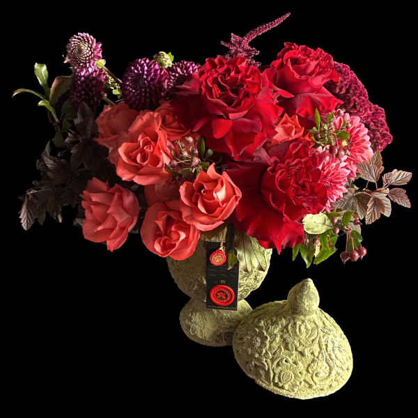Red and pink roses arranged in a decorative stone vase