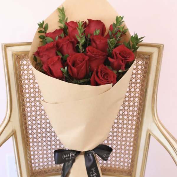 Bouquet of red roses wrapped in tan paper with a black ribbon