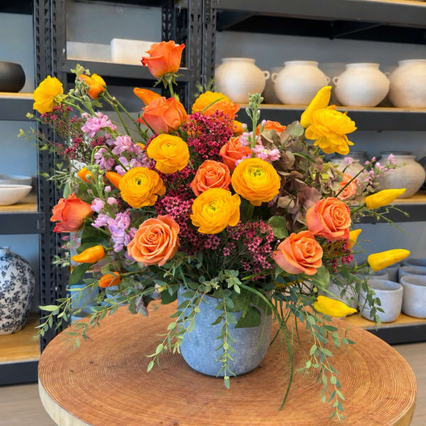 Orange and yellow rose arrangement in a blue vase