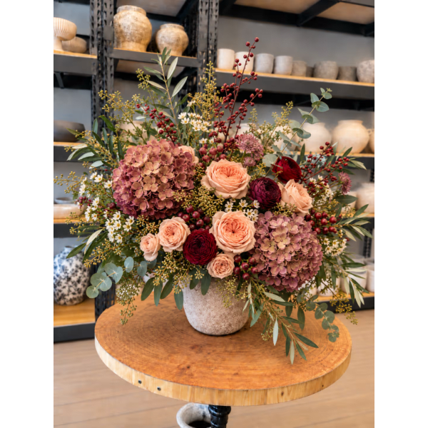 Large mixed floral arrangement in a textured vase on a round table