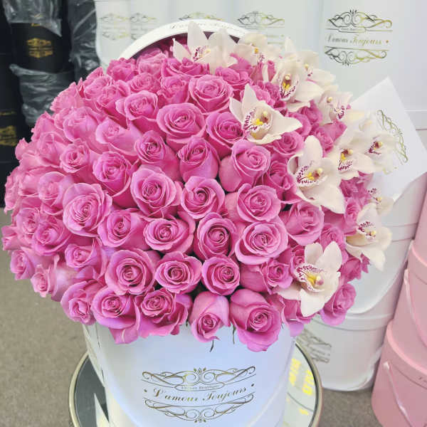 Pink roses and white orchids arranged in a white hat box