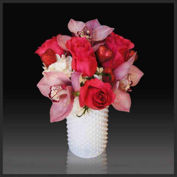 Pink roses and orchids arranged in a white vase