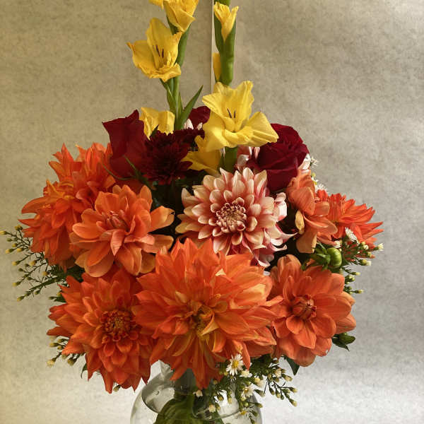 Orange and red flower arrangement in a clear glass vase