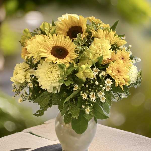 Yellow sunflower and chrysanthemum bouquet in a clear glass vase