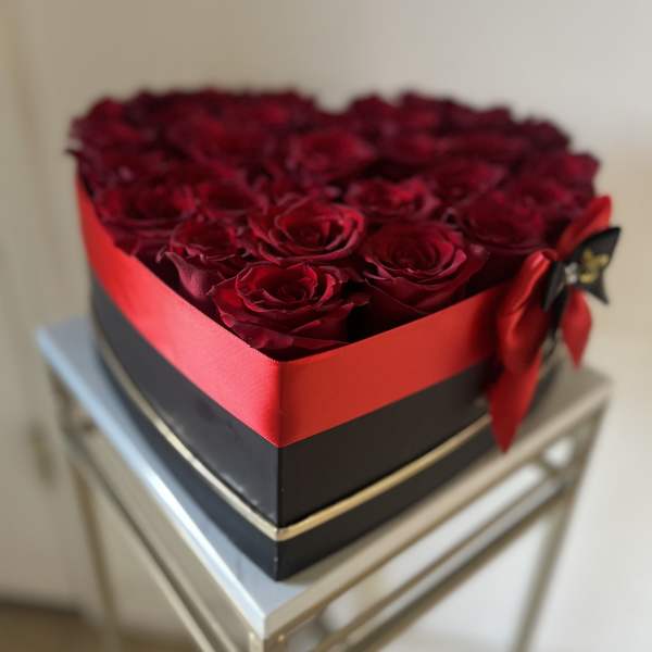 Heart-shaped box filled with red roses and tied with a red ribbon