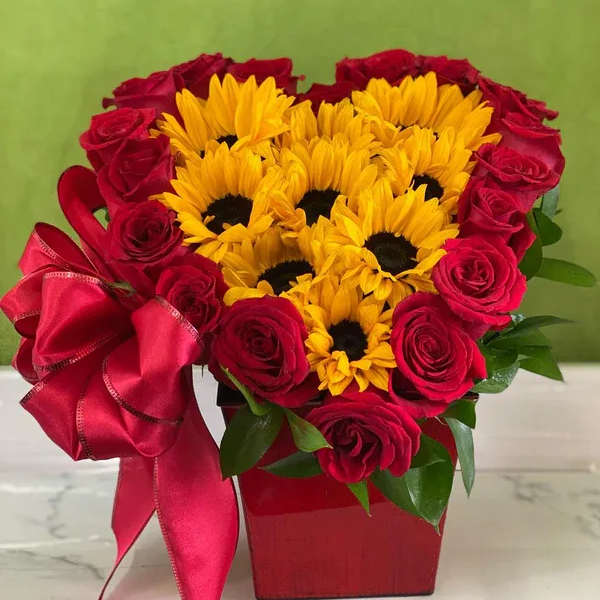 Heart-shaped bouquet of red roses and yellow sunflowers in a red box