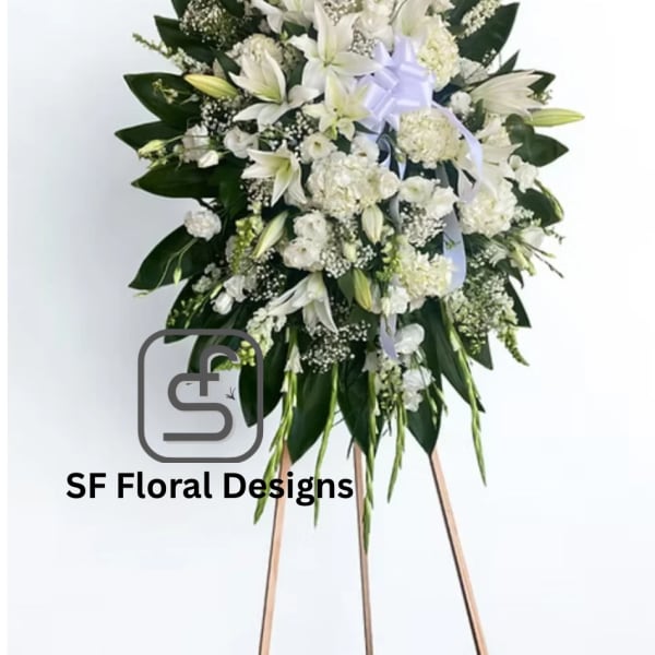 Tall white standing spray with lilies and other white flowers on a wooden easel