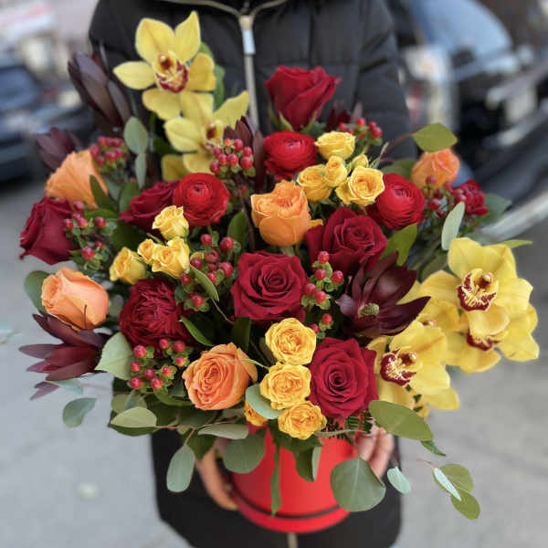 Bouquet of red, yellow, and peach roses with yellow orchids