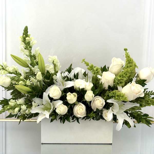 White roses and lilies arranged in a white rectangular box