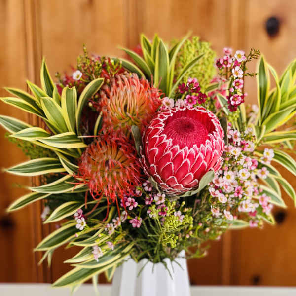 Tropical bouquet with pink protea in a white vase