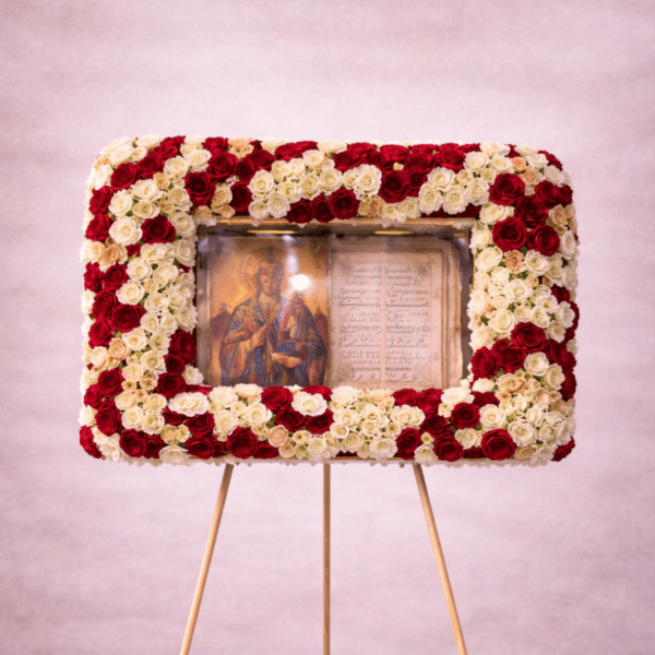 Tall standing rectangular wreath of red and white roses framing a religious icon on an easel.