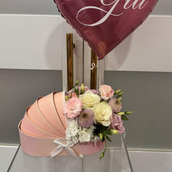 Pink heart balloon above a pastel flower box with roses and carnations