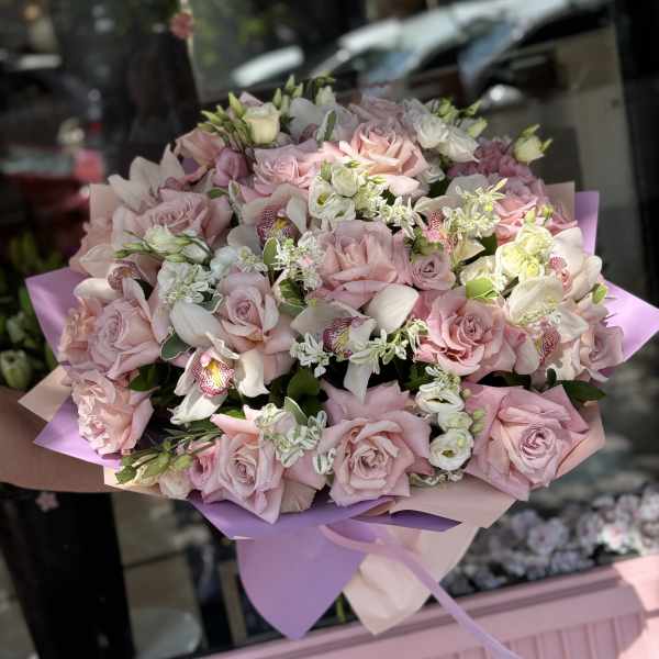 Large bouquet of pale pink roses and white orchids wrapped in lavender paper