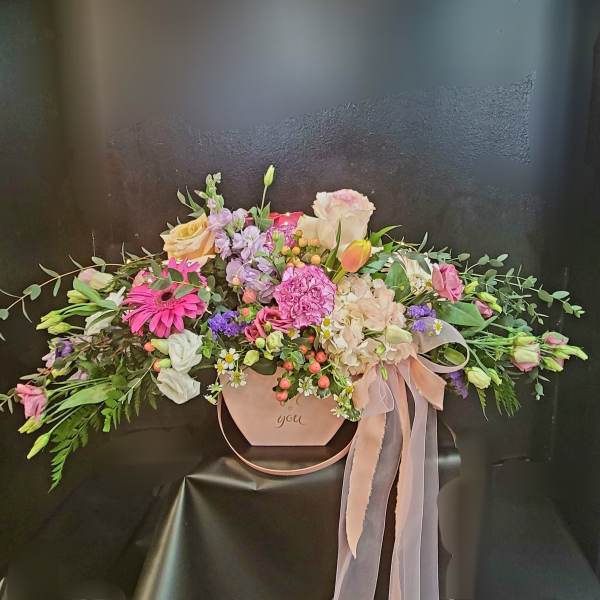Pastel floral arrangement in a pink hat box with ribbon