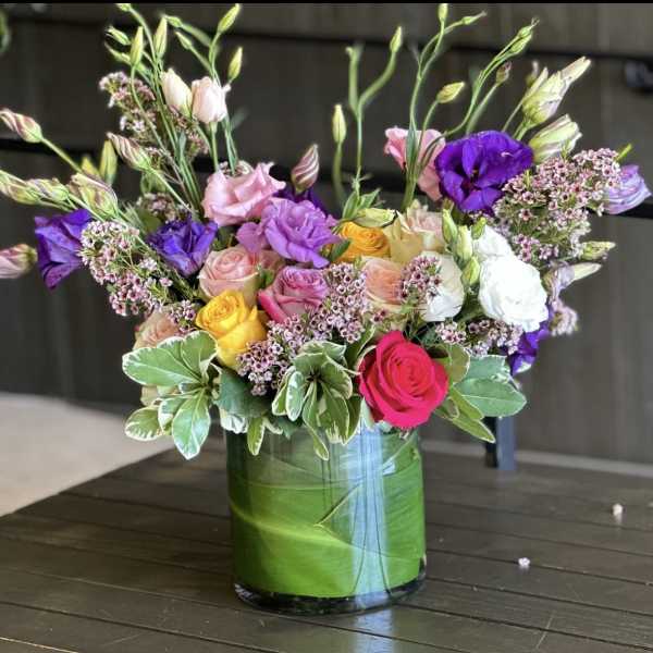 Mixed pink, purple, white, and yellow flowers in a glass vase