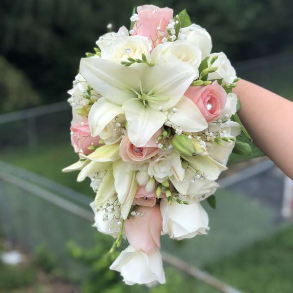 White lilies and blush roses in a hand-held bouquet