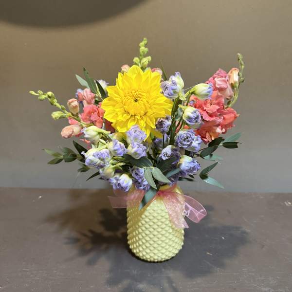 Colorful bouquet with a yellow dahlia in a textured vase