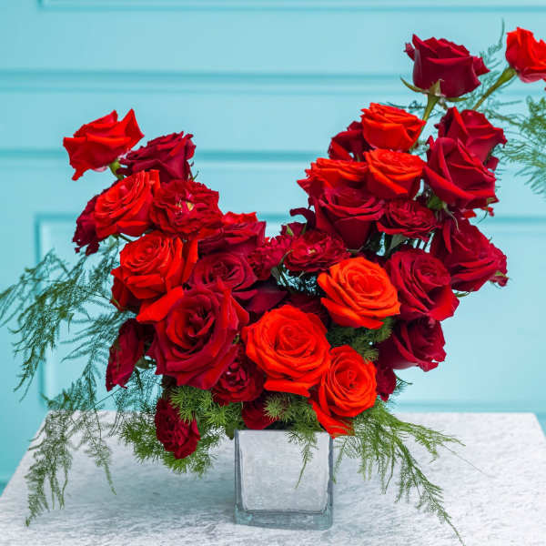 Red and orange roses in a clear square vase