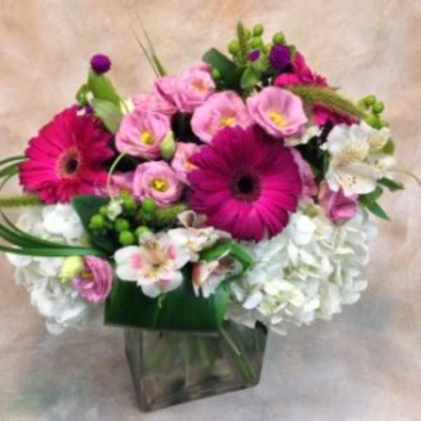 Pink and white mixed flower arrangement in a clear square vase