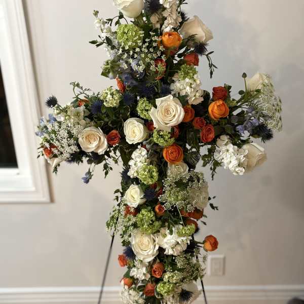 Tall floral cross with white, orange, blue, and green flowers