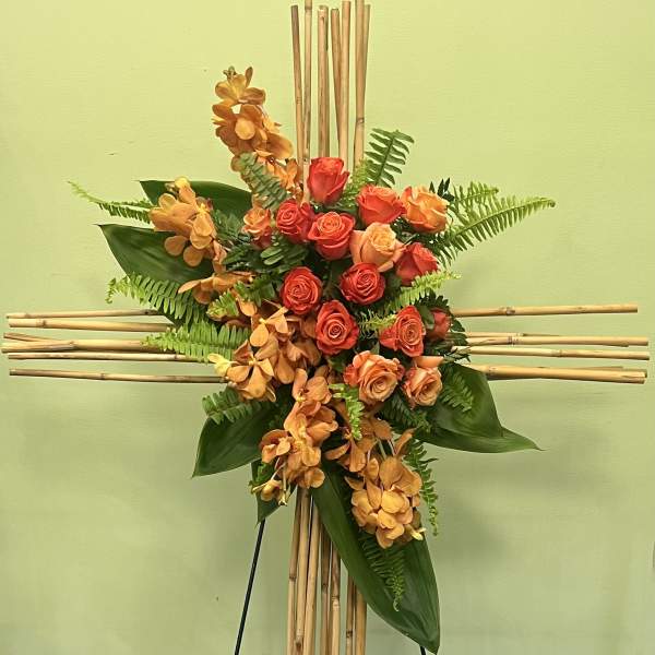 Orange roses and orchids arranged on a bamboo cross stand